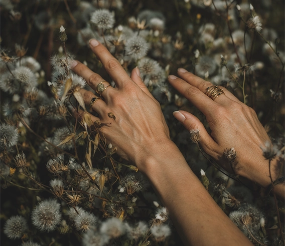 Dłonie kobiety dotykające przekwitniętych dmuchawców na łące – symbol kontaktu z naturą i alergenami wziewnymi